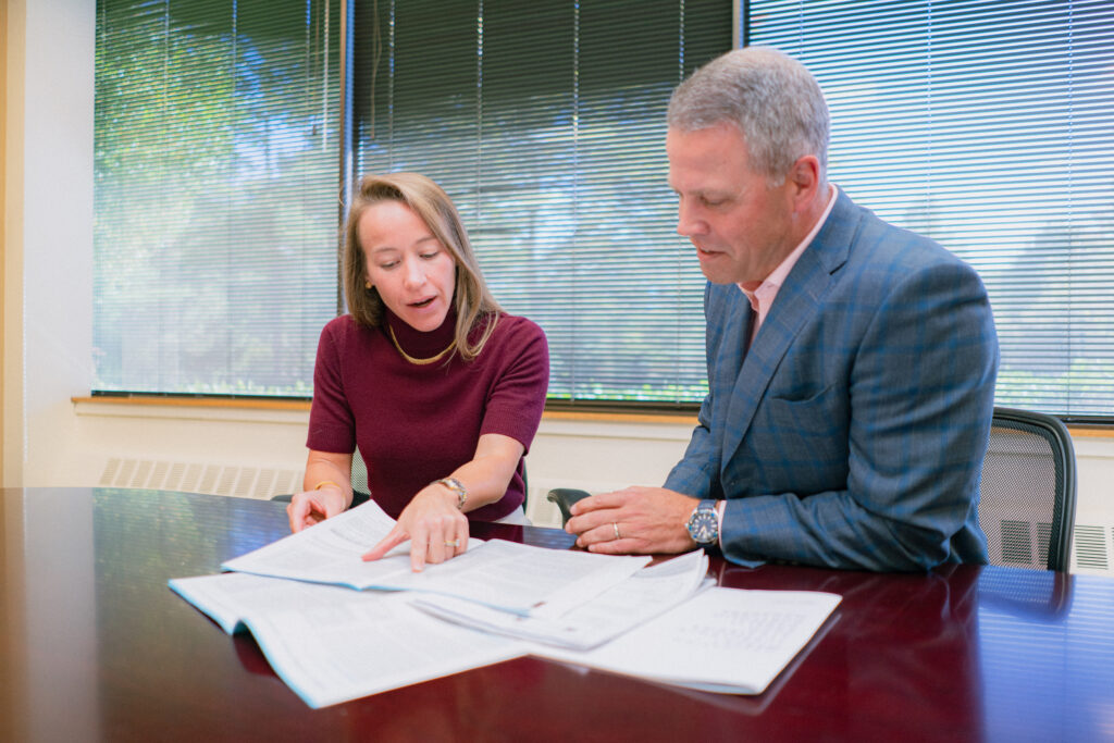 two people sitting at a table looking at papers together