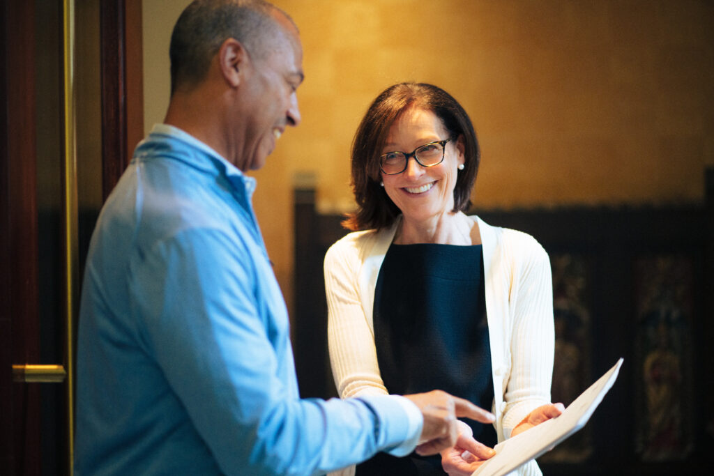 women looking at someone smiling and showing him something on a piece of paper