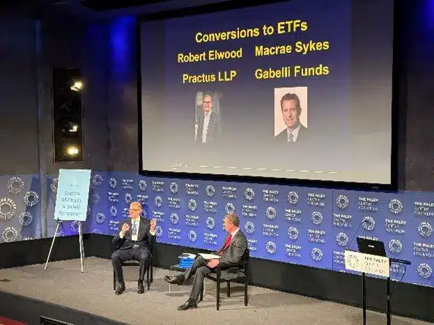 photo of two people speaking on a conference stage to an audience