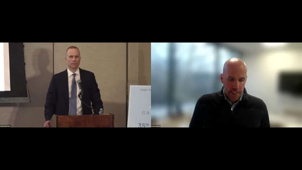 a man standing at a podium speaking to another man on a virtual call