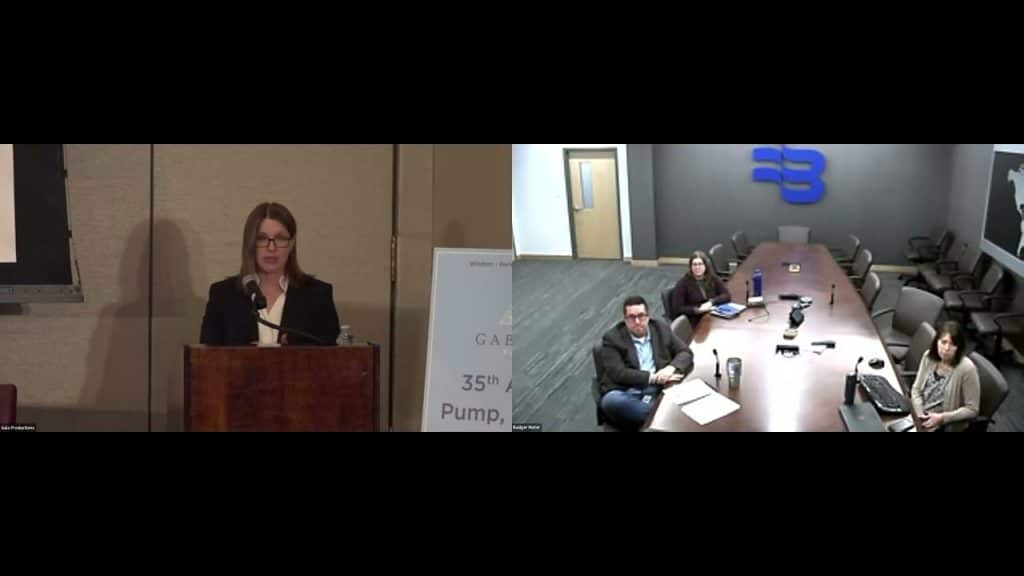 photo of a woman at a podium speaking to a board room of people